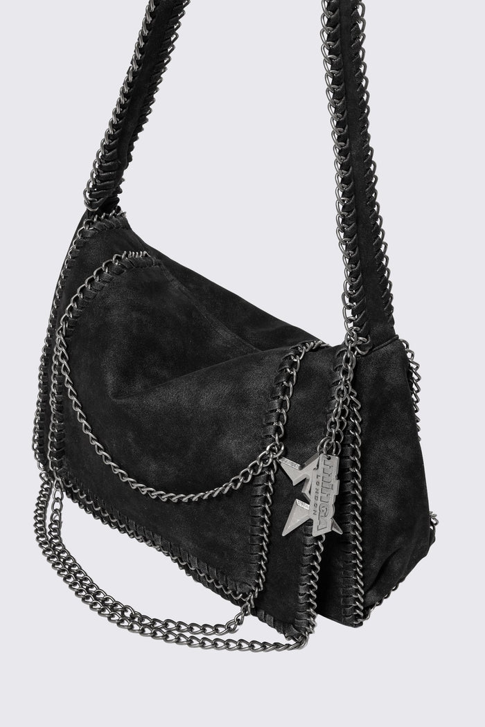 Black faux suede shoulder bag with chain trim, layered chains and fold-over flap in a grunge Y2K style.