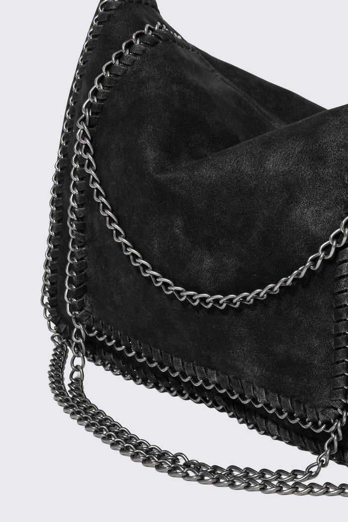 Black faux suede shoulder bag with chain trim, layered chains and fold-over flap in a grunge Y2K style.