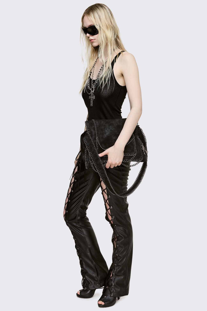 Black faux suede shoulder bag with chain trim, layered chains and fold-over flap in a grunge Y2K style.