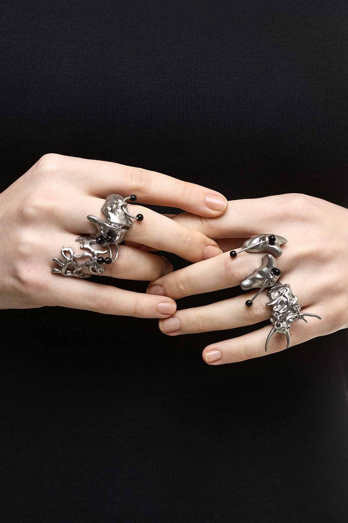 Antique-silver zinc ring set with sigilism shapes and black piercing details in a cyber goth style.