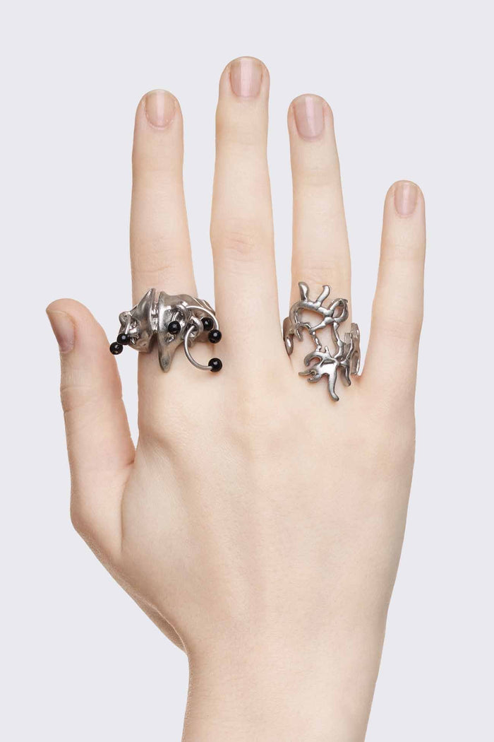 Antique-silver zinc ring set with sigilism shapes and black piercing details in a cyber goth style.