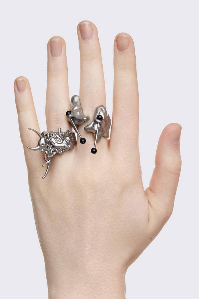 Antique-silver zinc ring set with sigilism shapes and black piercing details in a cyber goth style.