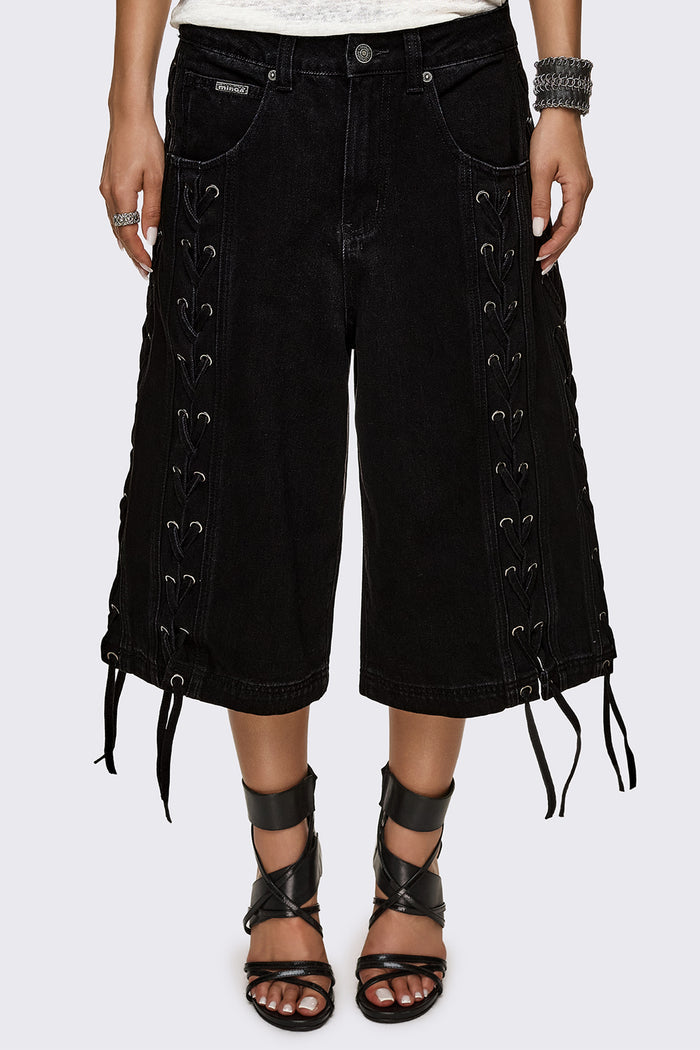 Black washed denim jorts with lace-up corset sides, baggy wide-leg fit and grunge aesthetic.