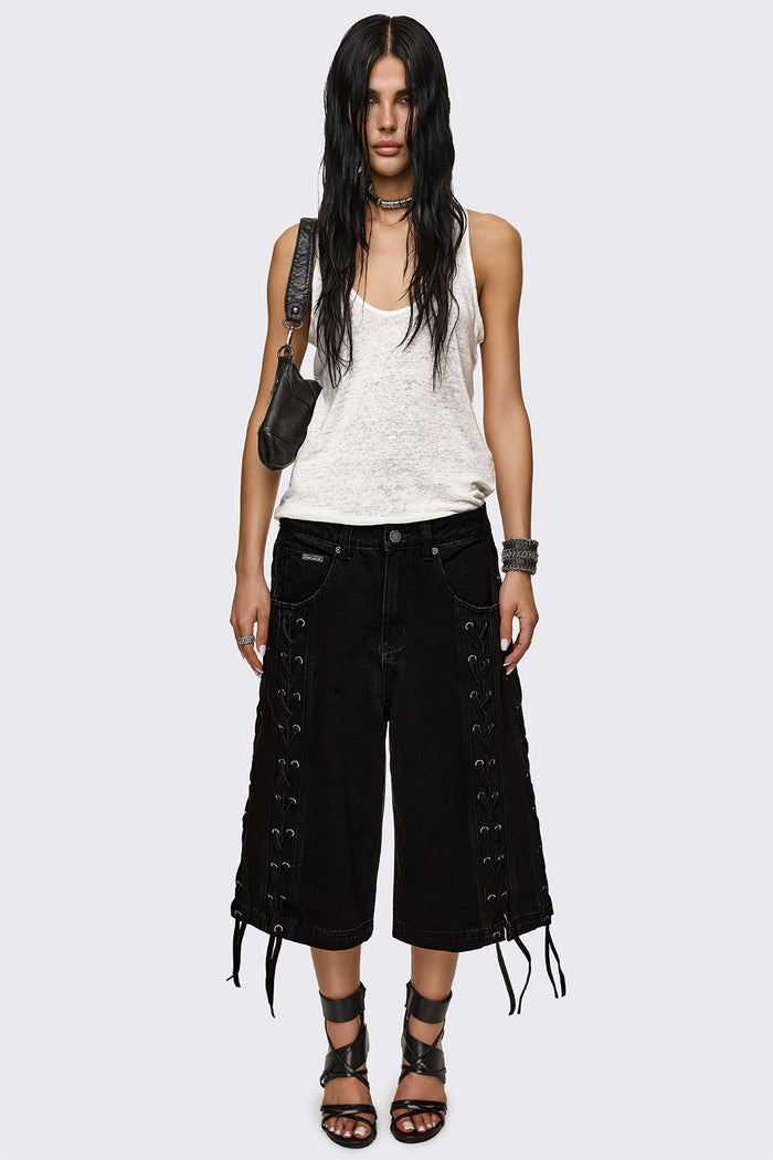 Black washed denim jorts with lace-up corset sides, baggy wide-leg fit and grunge aesthetic.