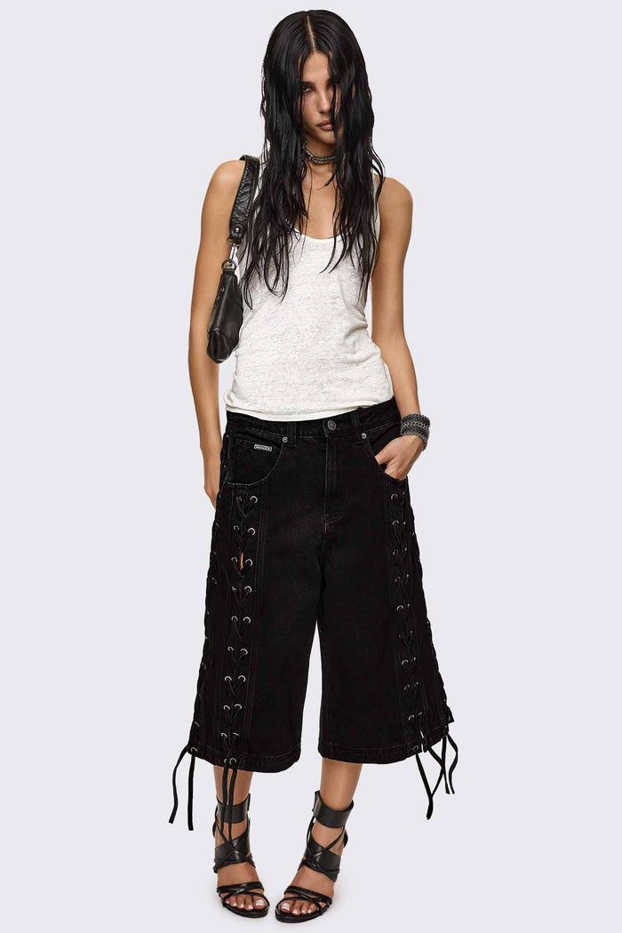 Black washed denim jorts with lace-up corset sides, baggy wide-leg fit and grunge aesthetic.