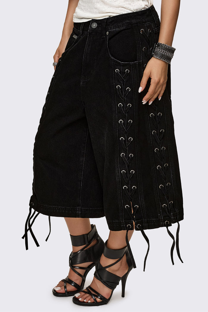 Black washed denim jorts with lace-up corset sides, baggy wide-leg fit and grunge aesthetic.