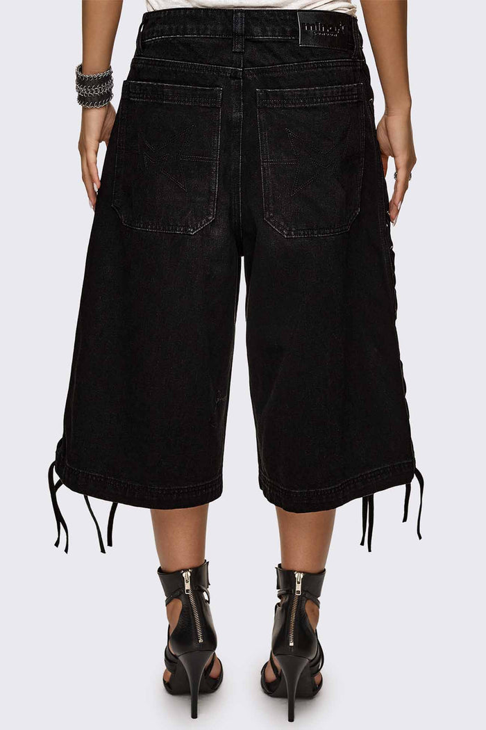 Black washed denim jorts with lace-up corset sides, baggy wide-leg fit and grunge aesthetic.